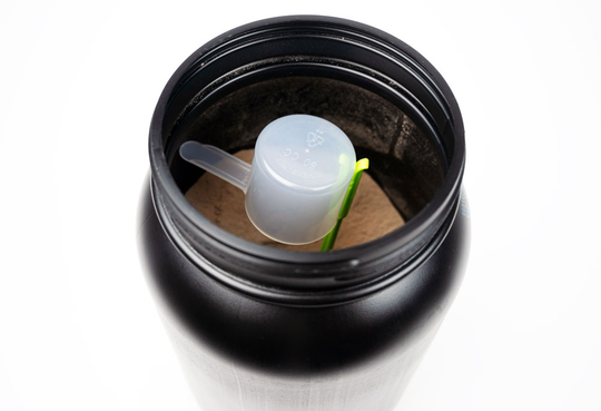 arial view of scoopjack holding scoop within reach in chocolate whey protein powder